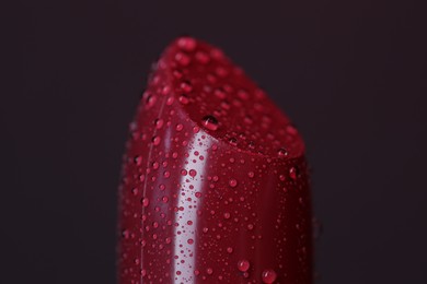 Beautiful red lipstick with water drops on dark background, macro view