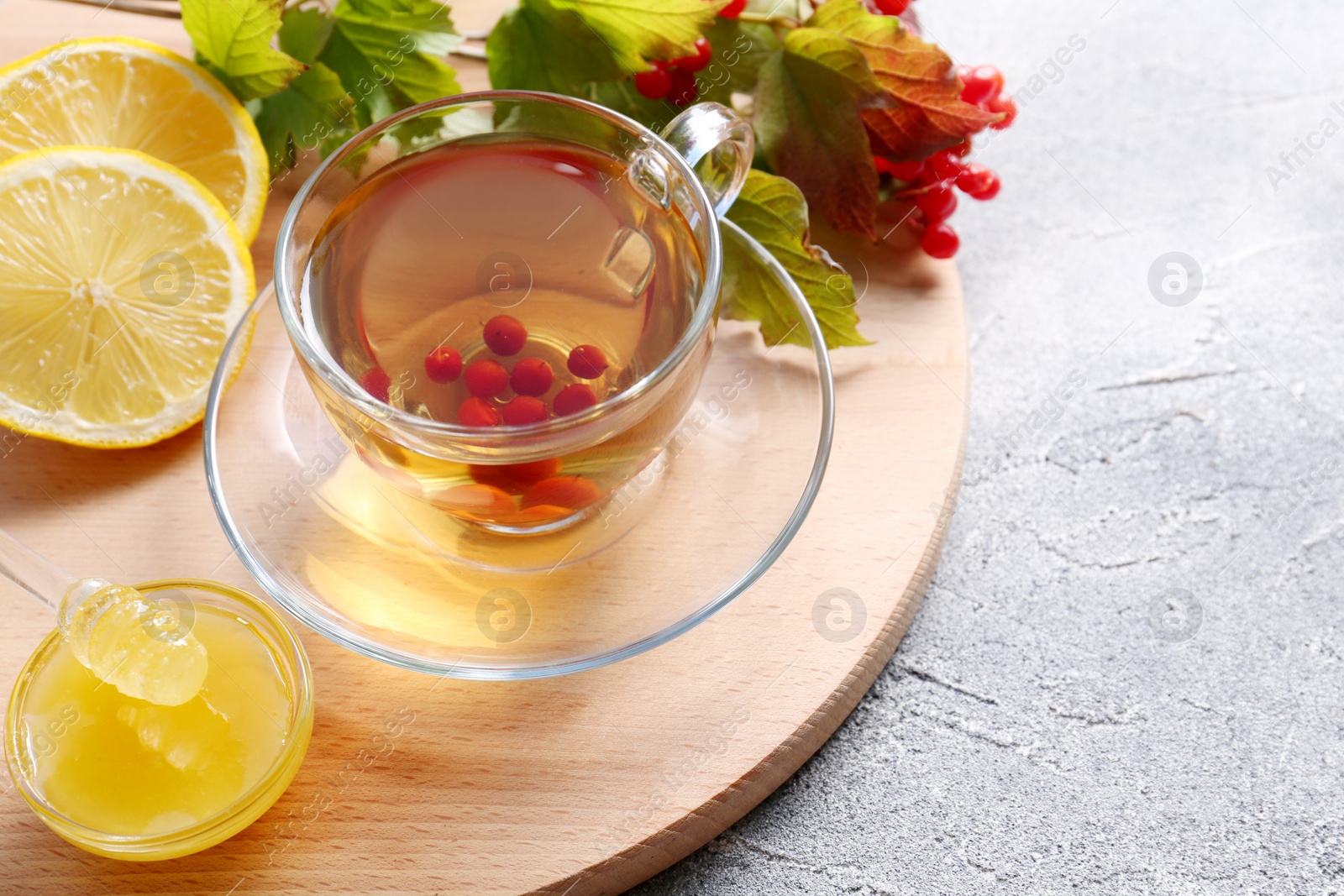 Photo of Cup of delicious tea with lemon, honey and viburnum on light grey table, above view. Space for text