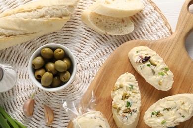 Photo of Tasty butter with olives, green onion, garlic and bread on table, top view