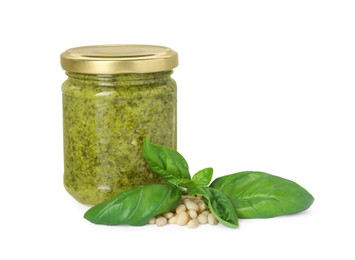 Photo of Delicious pesto sauce in jar, pine nuts and basil leaves isolated on white