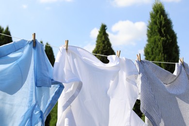 Photo of Clean clothes hanging on washing line outdoors. Drying laundry