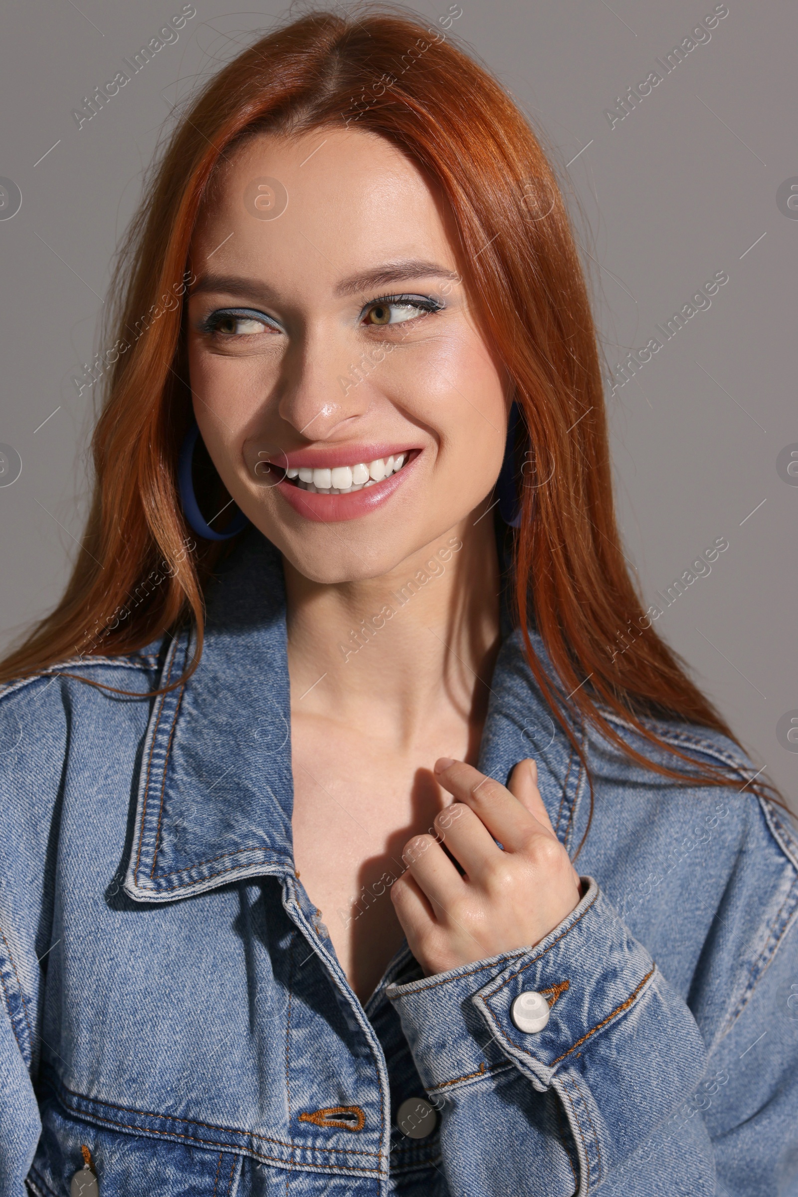 Photo of Beautiful young woman in denim jacket on gray background