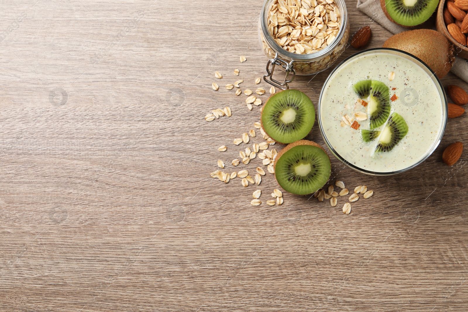 Photo of Glass of tasty kiwi smoothie with oatmeal on wooden table, flat lay. Space for text