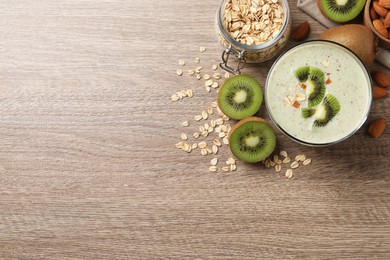 Photo of Glass of tasty kiwi smoothie with oatmeal on wooden table, flat lay. Space for text