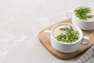 Bowls with tasty creamy soup of parsnip on color textured table, space for text