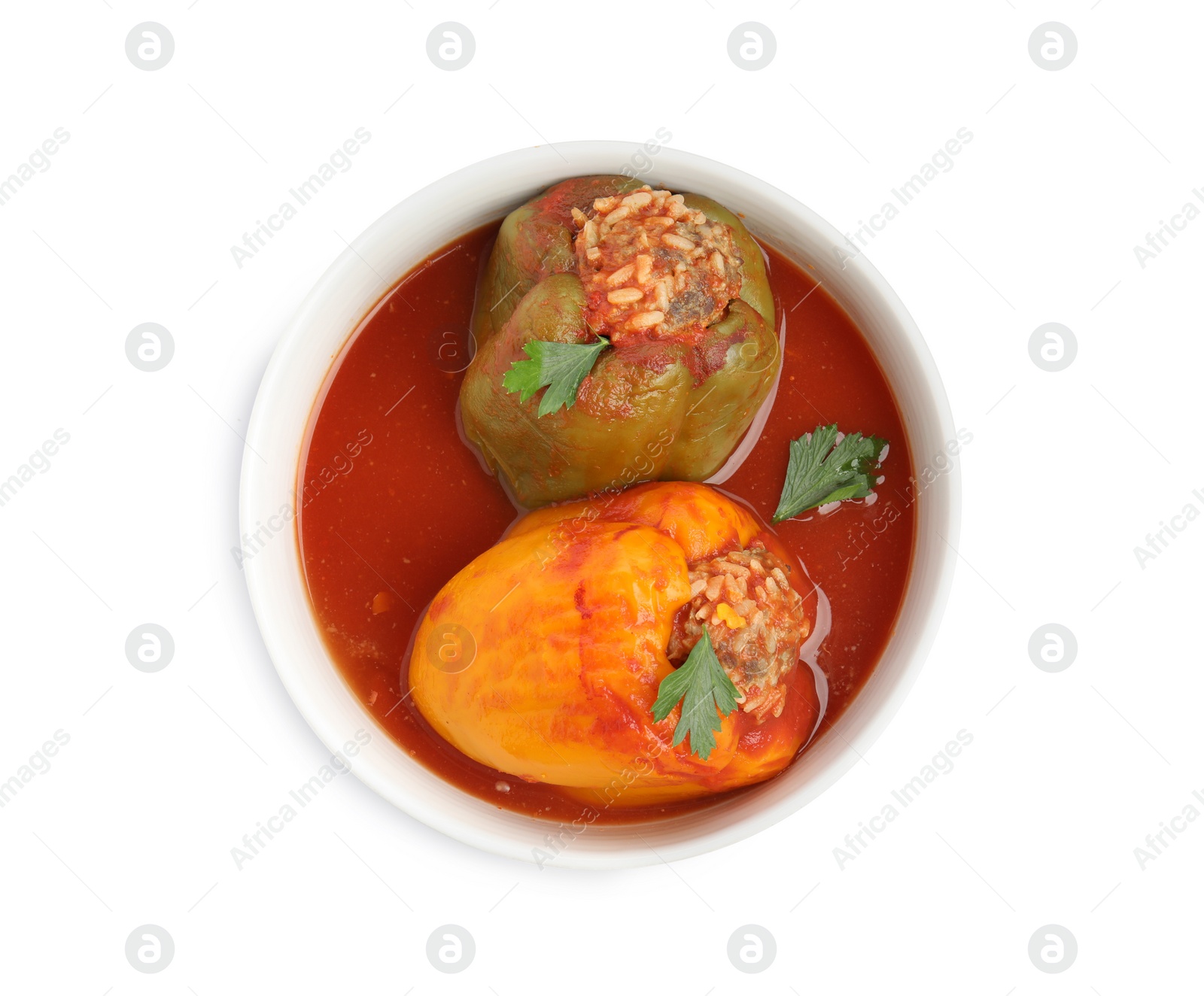 Photo of Delicious stuffed peppers with parsley in bowl isolated on white, top view