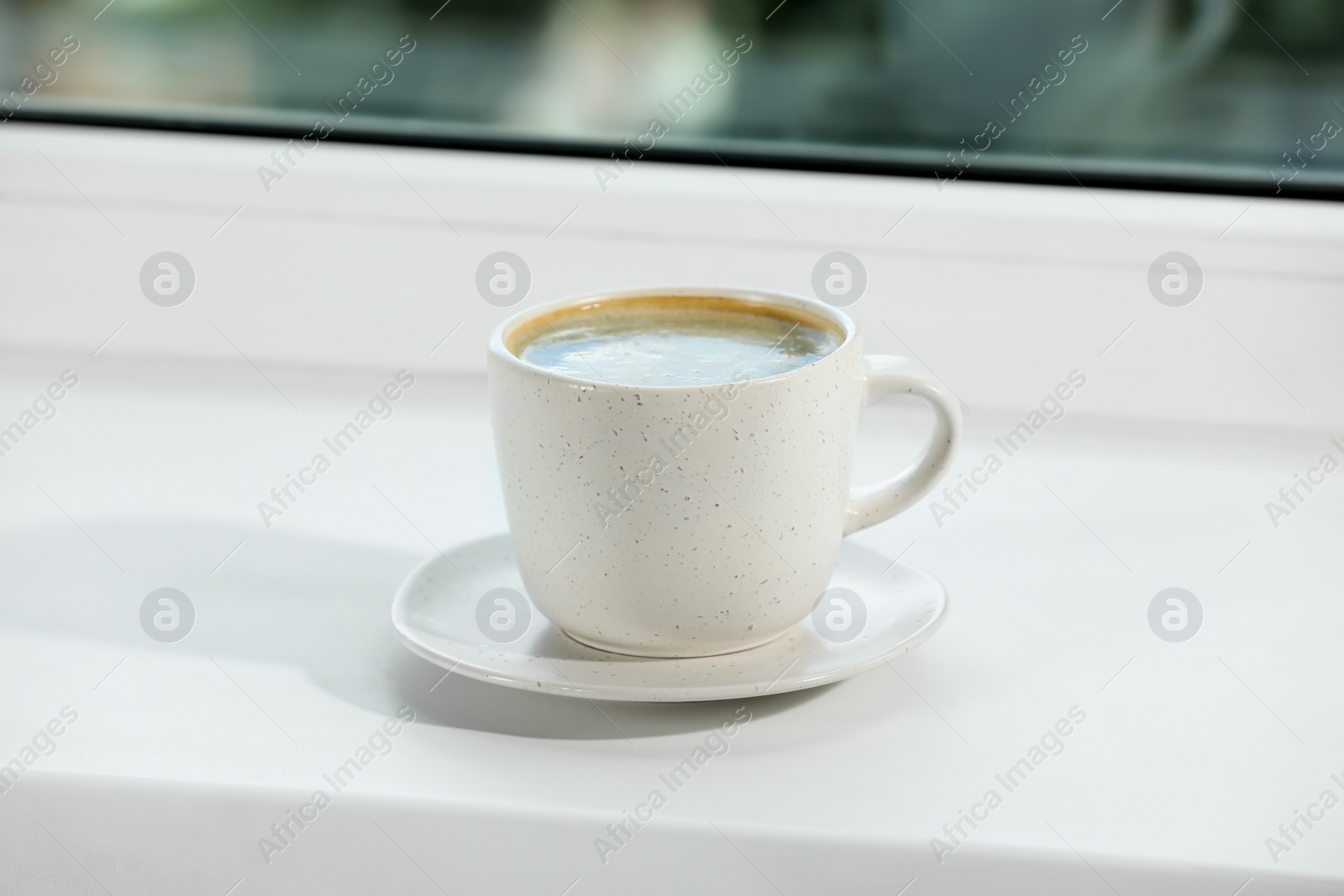 Photo of Cup of aromatic coffee on white sill near window indoors