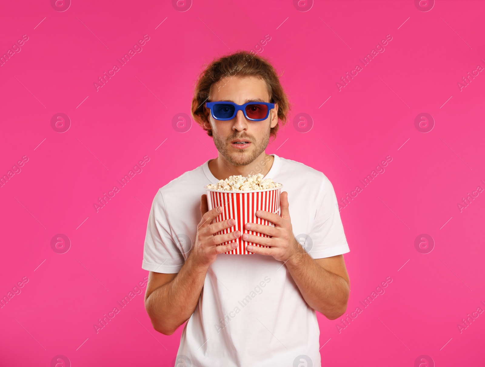 Photo of Emotional man with 3D glasses and popcorn during cinema show on color background