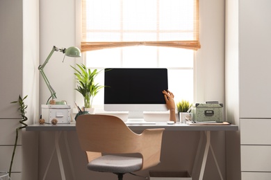 Photo of Light work place with computer near window at home. Interior design