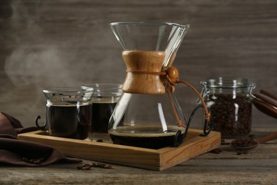 Glass chemex coffeemaker with coffee and beans on wooden table