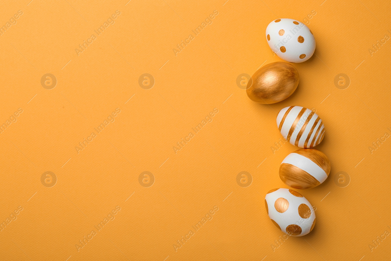 Photo of Set of traditional Easter eggs decorated with golden paint on color background, top view. Space for text