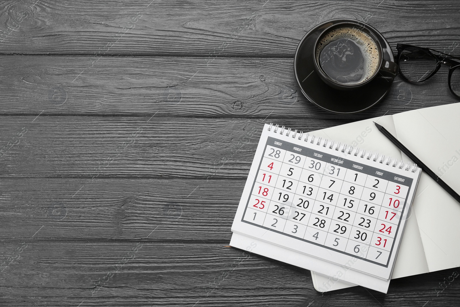 Photo of Flat lay composition with calendar and cup of coffee on grey wooden table. Space for text