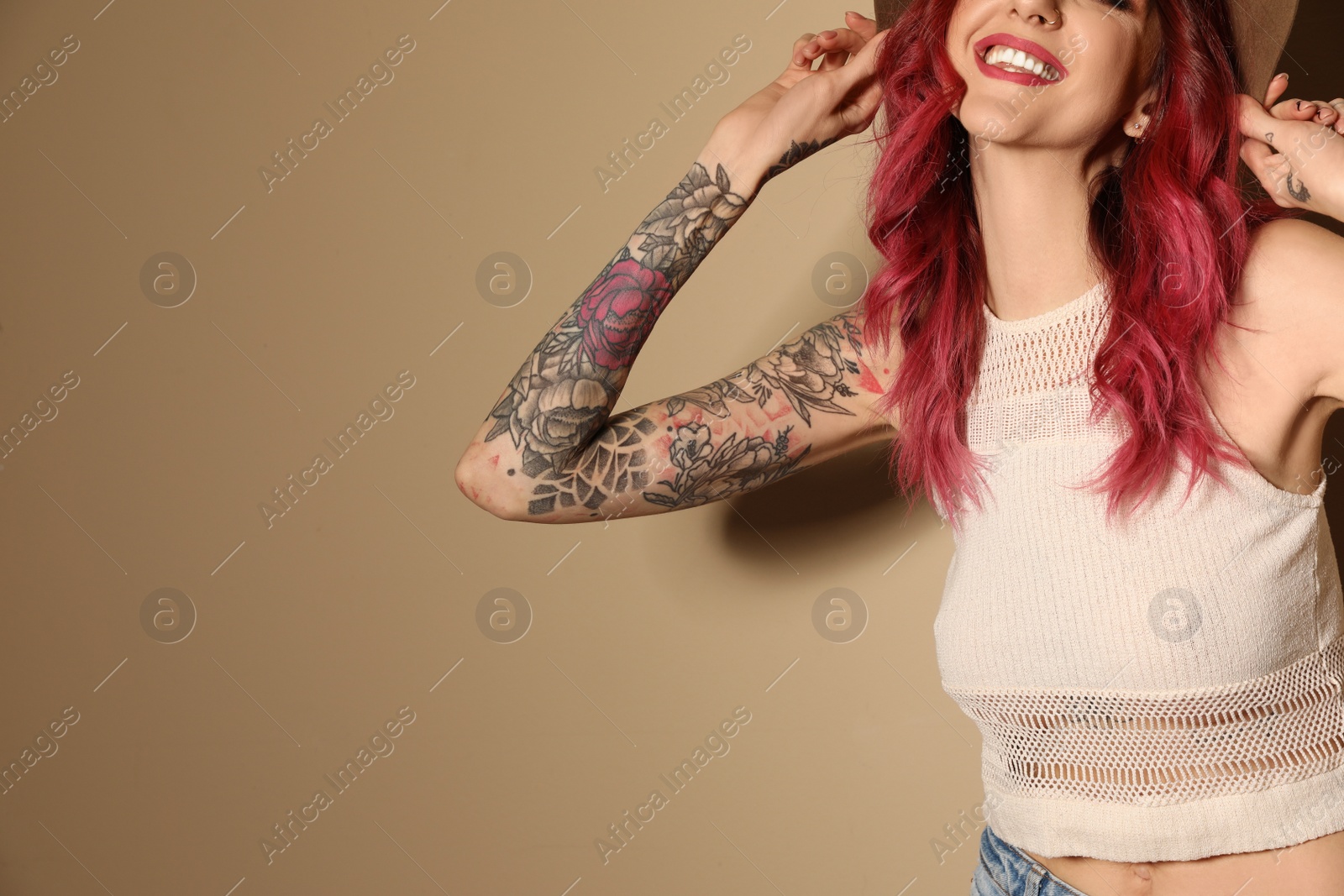 Photo of Beautiful woman with tattoos on arms against beige background, closeup. Space for text