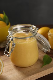 Delicious lemon curd in glass jar and green leaf on table