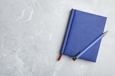 Photo of Stylish notebook and pen on marble table, top view. Space for text