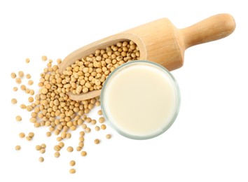 Glass of fresh soy milk and scoop with beans on white background, top view