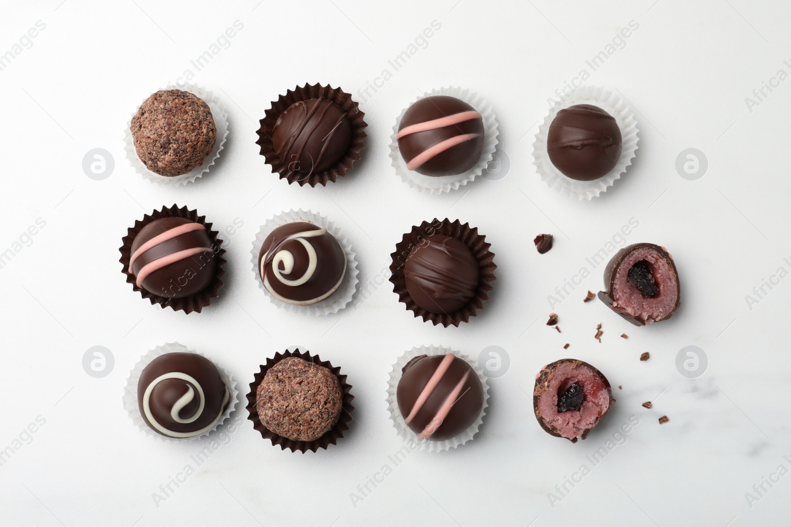 Photo of Different delicious chocolate truffles on white marble table, flat lay