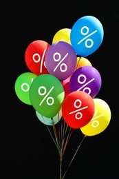 Image of Discount offer. Bunch of balloons with percent signs against black background