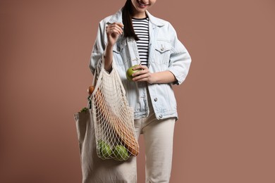 Woman with eco bags full of products on pink background