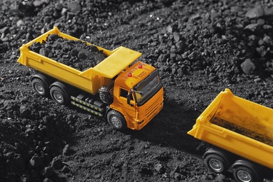 Image of Toy tipper trucks with coal in field