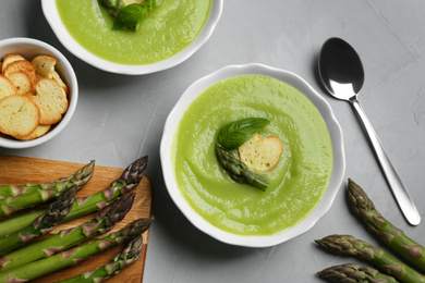 Photo of Delicious asparagus soup served on grey table, flat lay