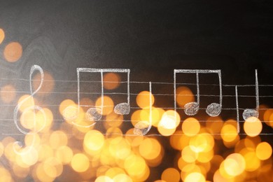 Image of Christmas and New Year music. Chalked music notes on blackboard, bokeh effect