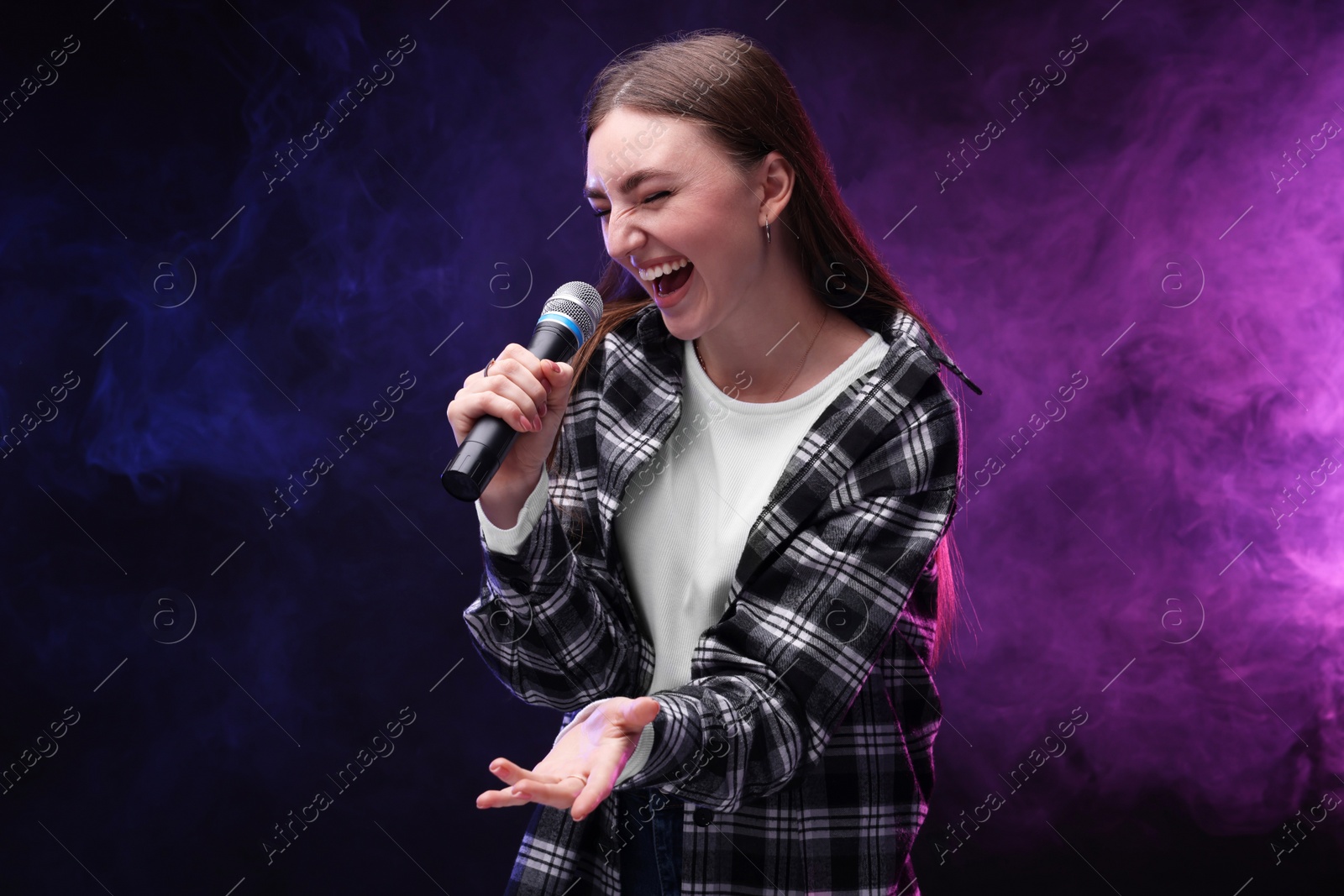 Photo of Emotional woman with microphone singing in color lights