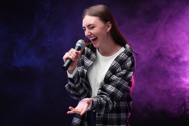 Emotional woman with microphone singing in color lights