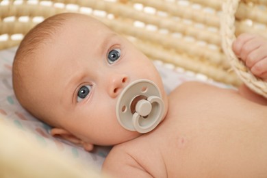 Cute little baby with pacifier lying in cradle