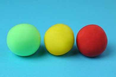 Photo of Different color play dough balls on light blue background