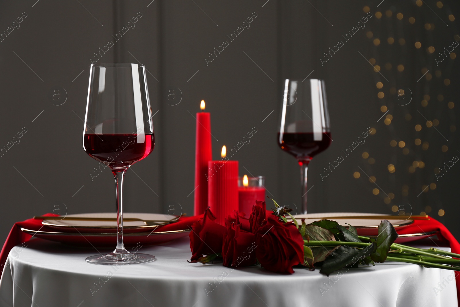 Photo of Place setting with roses and candles on white table. Romantic dinner