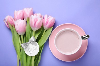 Cup of hot drink, beautiful tulips and card with text Good Morning on light purple background, flat lay