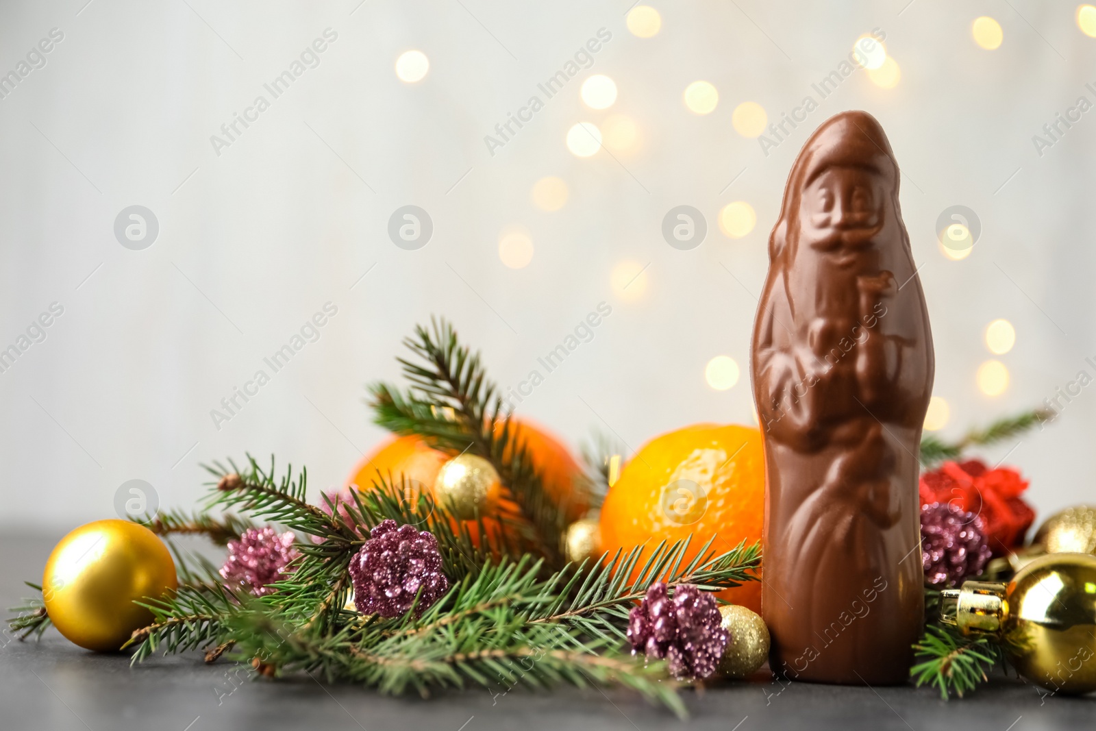 Photo of Composition with chocolate Santa Claus, tangerine fruits and Christmas decorations on light grey background, space for text