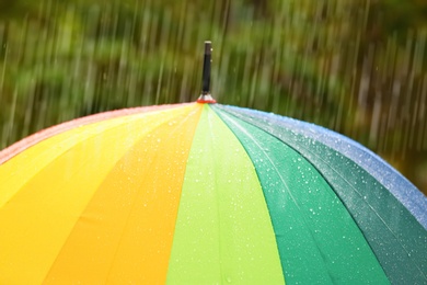 Photo of Bright umbrella under rain on street, closeup