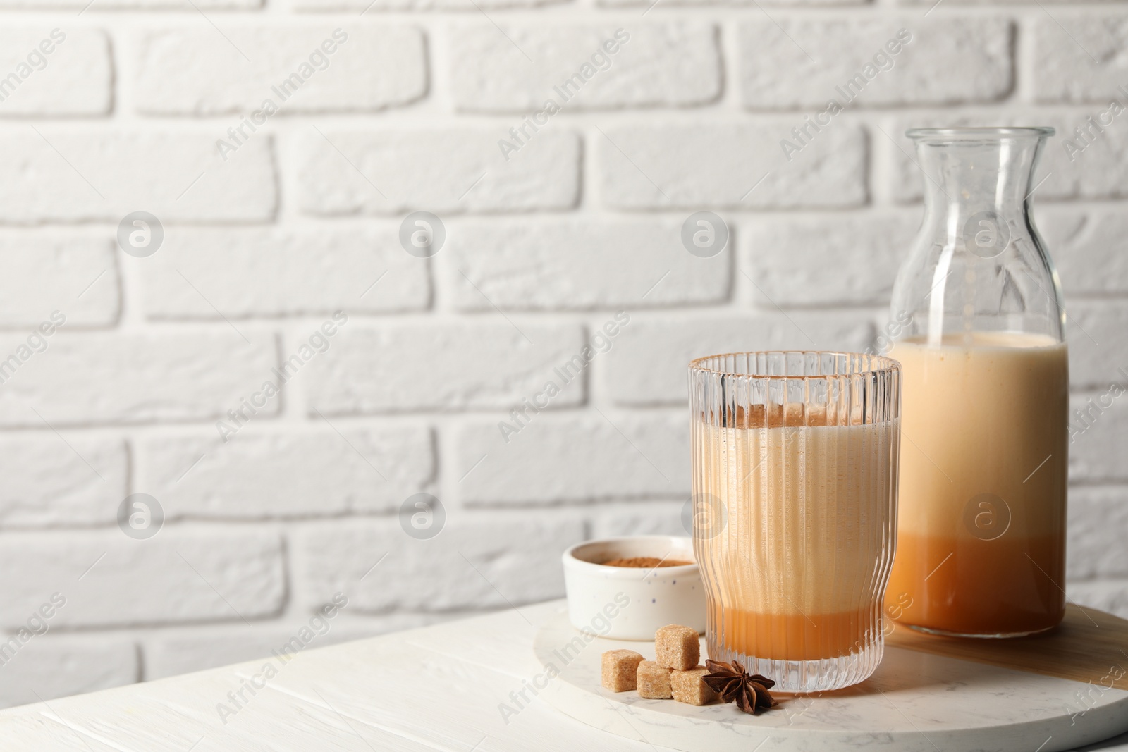 Photo of Delicious eggnog with anise and sugar on white wooden table. Space for text