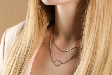 Photo of Woman wearing stylish metal chains, closeup. Luxury jewelry