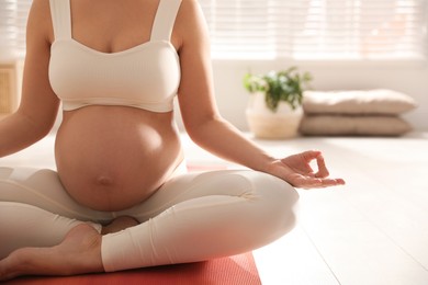 Young pregnant woman practicing yoga at home, closeup