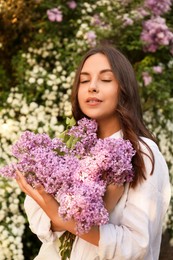 Photo of Attractive young woman with lilac flowers outdoors