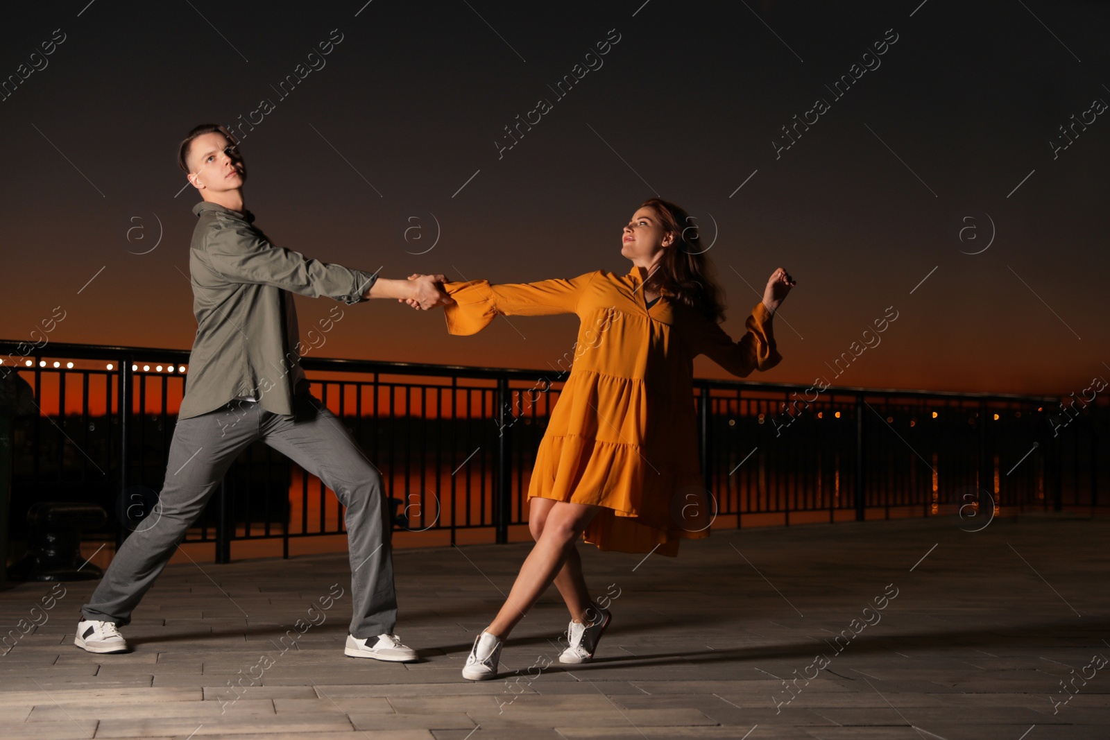 Photo of Beautiful young couple practicing dance moves in evening outdoors