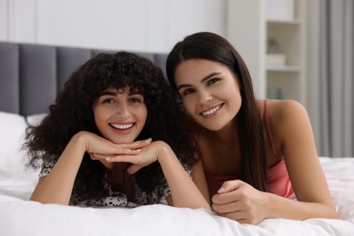 Photo of Portrait of happy young friends on bed at home