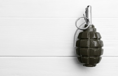 Photo of Hand grenade on white wooden table, top view. Space for text