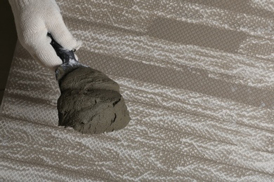 Photo of Worker holding adhesive mix on spatula above tile, closeup. Space for text