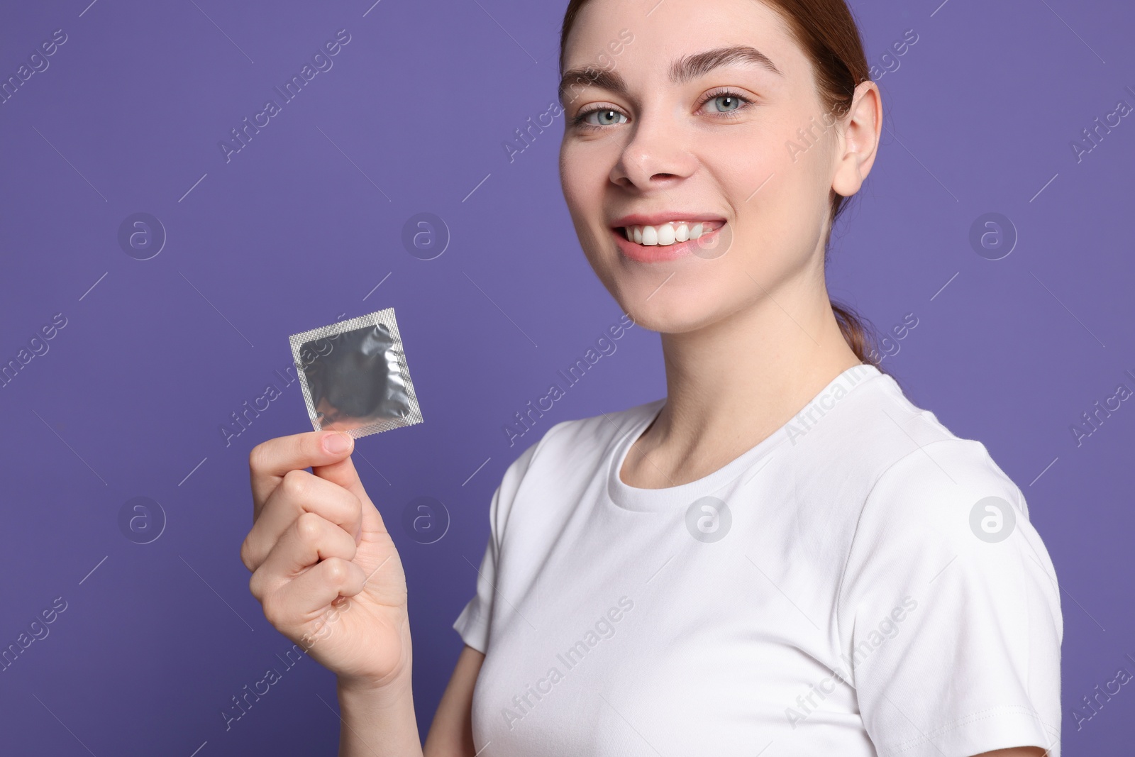 Photo of Woman holding condom on purple background. Safe sex