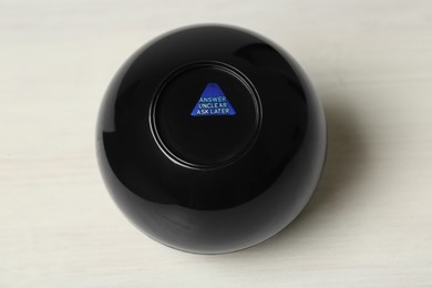 Photo of Magic eight ball with prediction Answer Unclear Ask Later on white table, above view