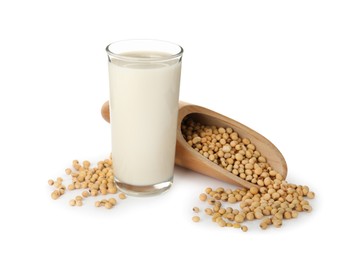 Glass of fresh soy milk and scoop with beans on white background