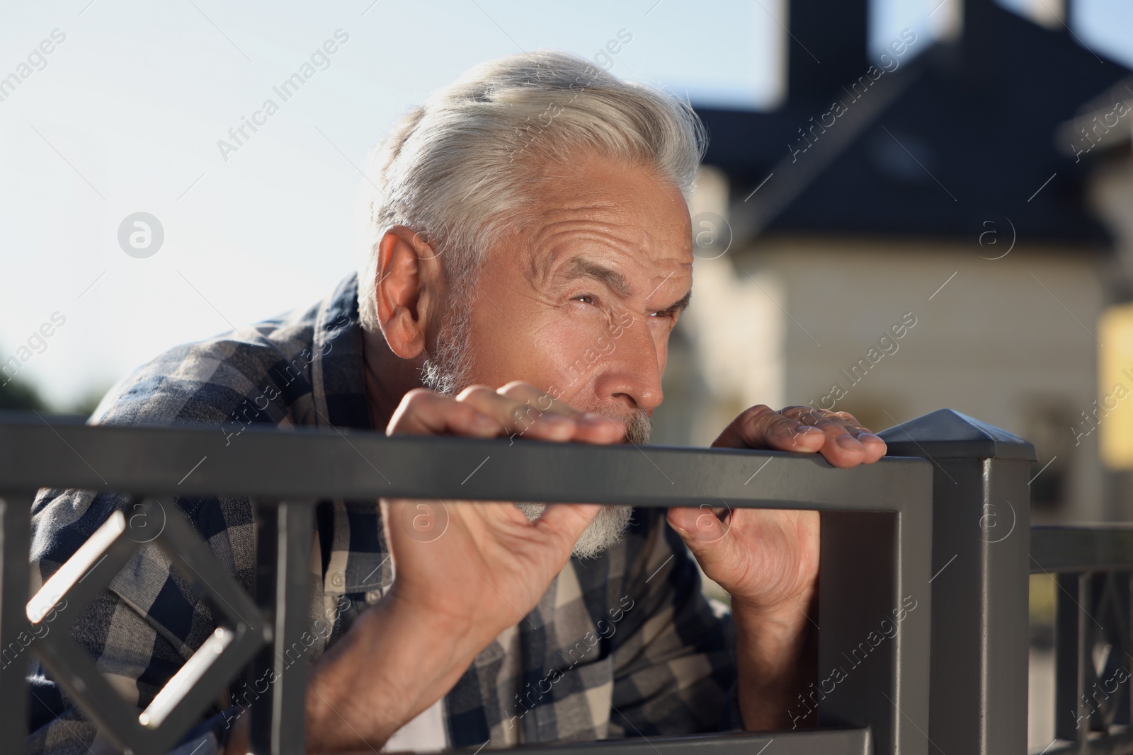 Photo of Concept of private life. Curious senior man spying on neighbours over fence outdoors