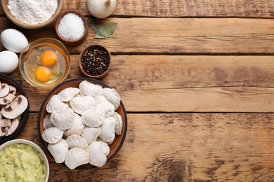 Photo of Raw dumplings (varenyky) and ingredients on wooden table, flat lay. Space for text