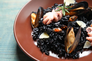 Photo of Delicious black risotto with seafood on blue wooden table, closeup