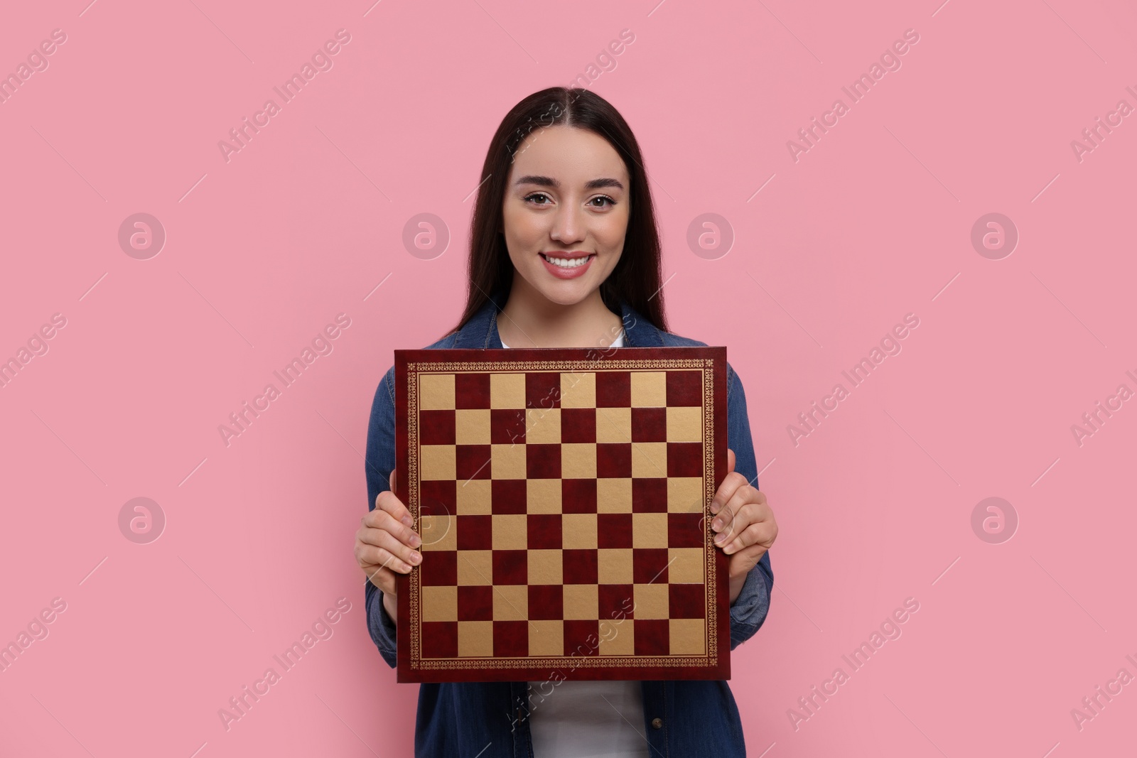 Photo of Happy woman with chessboard on pink background