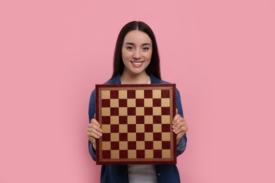 Photo of Happy woman with chessboard on pink background